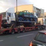 A pickup on a dumptruck on a flatbed on a massive truck